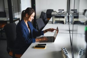 Beautiful elegant web designer working at the laptop while using internet in the workspace