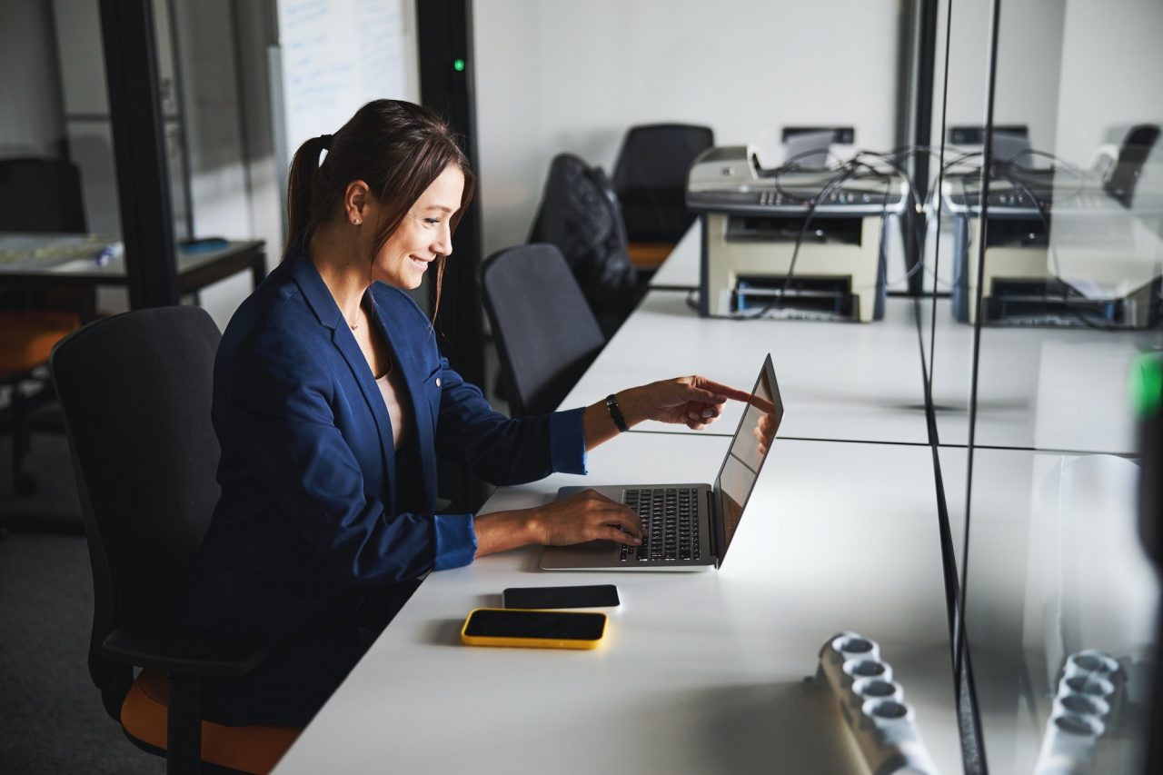 Beautiful elegant web designer working at the laptop while using internet in the workspace